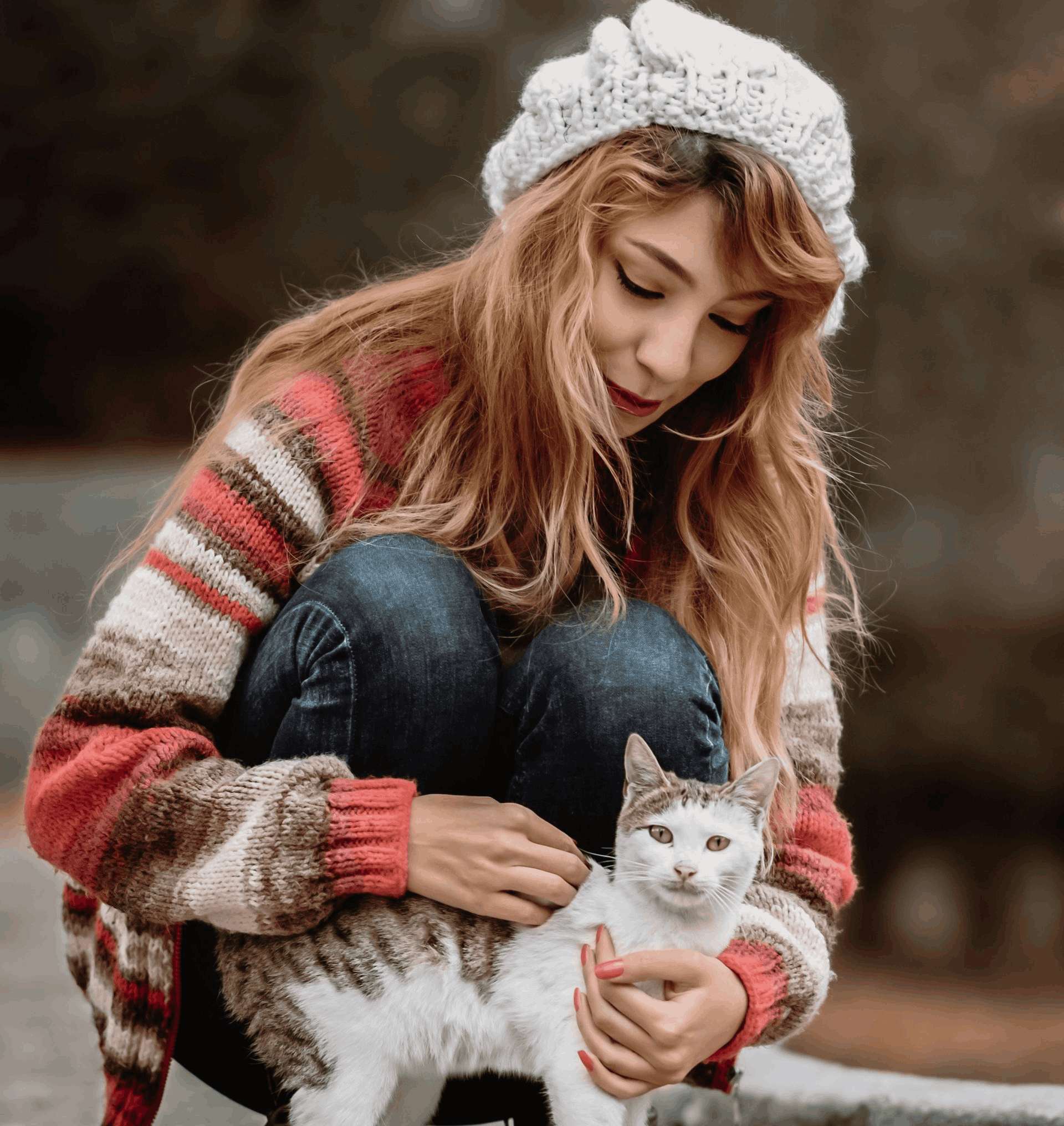 Woman in cosy sweater cuddling a white and tabby cat