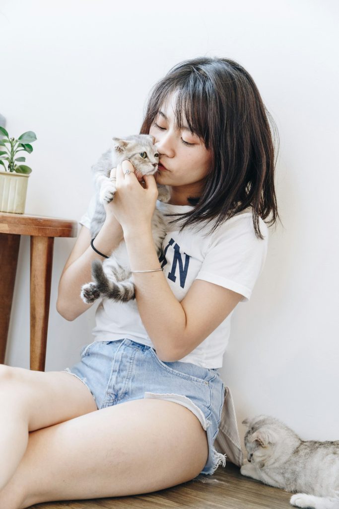 Woman gently kissing a kitten in a bright room